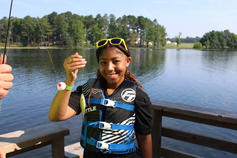 A camper holds up a fish she caught on the lake
