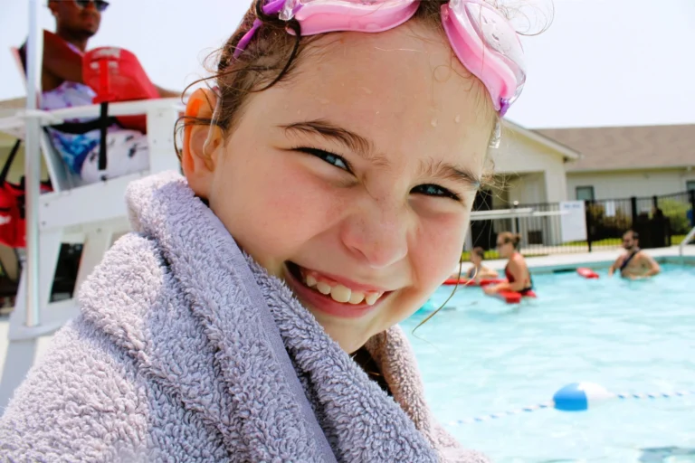 A camper smiles while wearing goggles at the pool