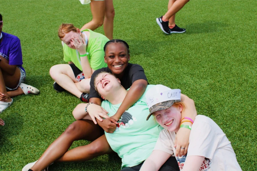 Campers play on the lawn, hugging